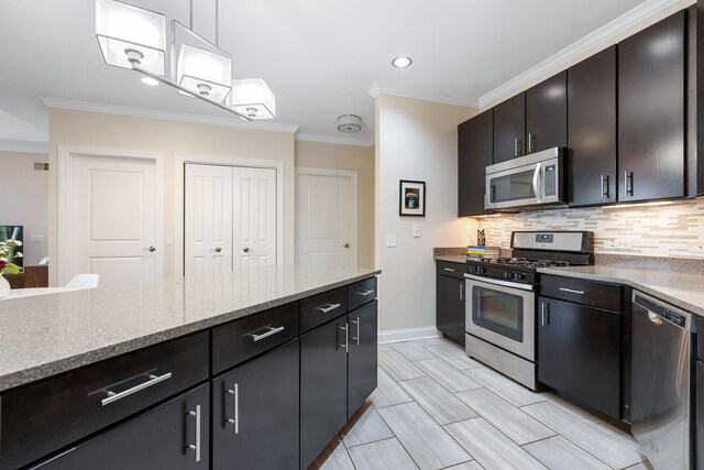 kitchen with appliances with stainless steel finishes, hanging light fixtures, light stone countertops, crown molding, and backsplash