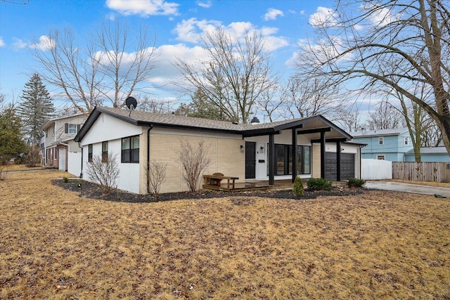 view of front facade with a garage, driveway, fence, and brick siding