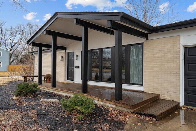 doorway to property with an attached garage and brick siding