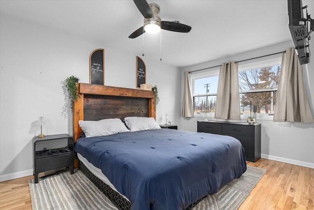 bedroom featuring light wood-type flooring, a ceiling fan, and baseboards