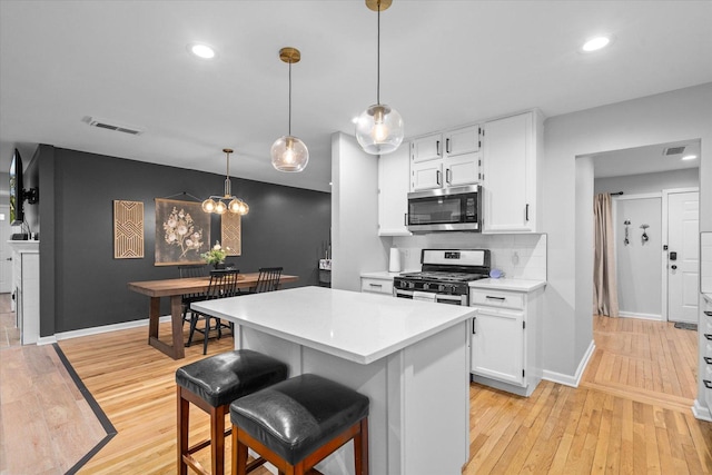 kitchen with white cabinetry, light wood-style floors, light countertops, appliances with stainless steel finishes, and decorative backsplash