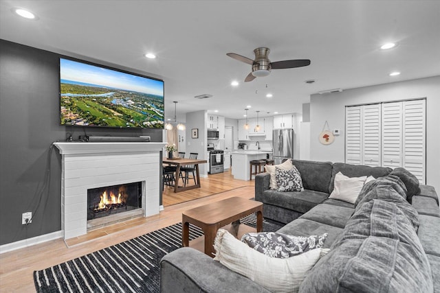 living area featuring light wood-type flooring, ceiling fan, baseboards, and recessed lighting