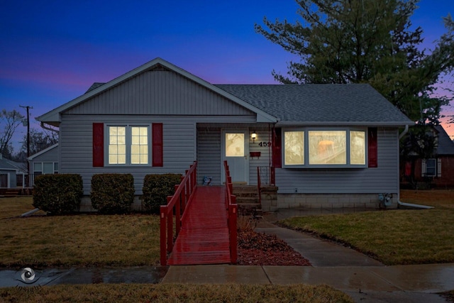 view of front of home featuring roof with shingles and a yard