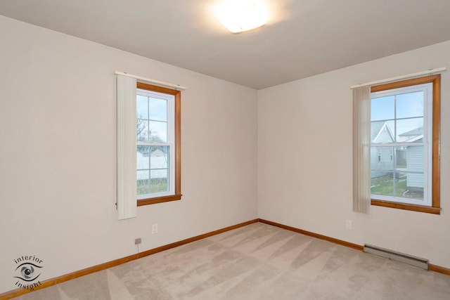 spare room featuring light carpet, plenty of natural light, a baseboard radiator, and baseboards