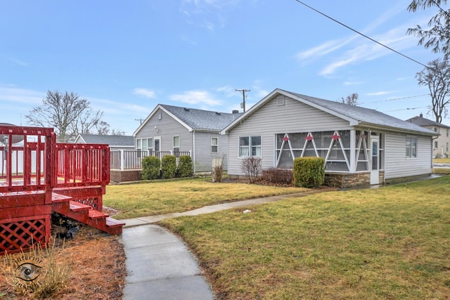 back of house featuring a lawn, a wooden deck, and a sunroom