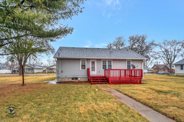 rear view of property featuring roof with shingles, a deck, and a yard