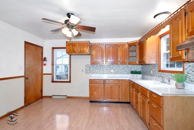 kitchen featuring brown cabinetry, light countertops, a sink, and light wood finished floors