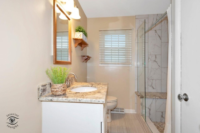 full bathroom featuring toilet, vanity, visible vents, baseboards, and a marble finish shower