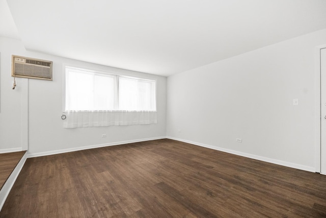 unfurnished room with baseboards, dark wood-type flooring, and a wall mounted AC