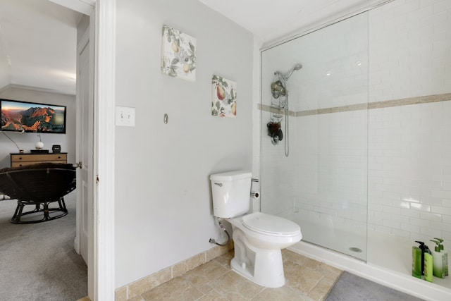 bathroom with toilet, baseboards, and a tile shower