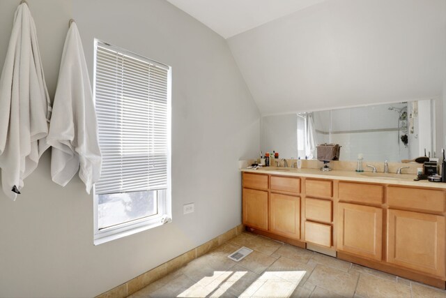 bathroom featuring visible vents, lofted ceiling, double vanity, stone finish floor, and a sink