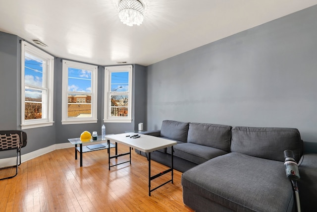 living area featuring an inviting chandelier, visible vents, baseboards, and light wood finished floors