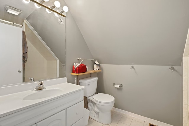 bathroom featuring vanity, baseboards, vaulted ceiling, tile patterned floors, and toilet