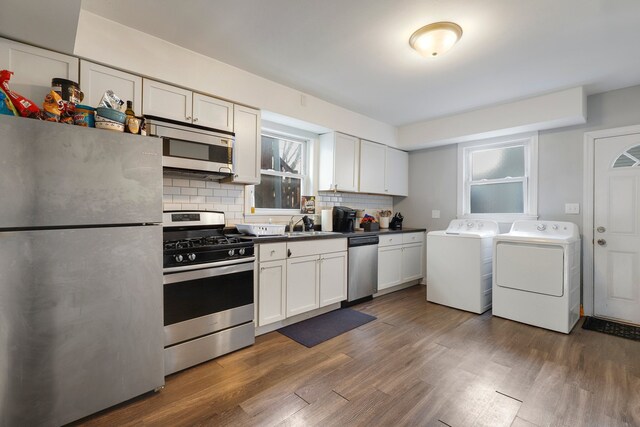 kitchen with dark wood finished floors, white cabinets, appliances with stainless steel finishes, independent washer and dryer, and backsplash