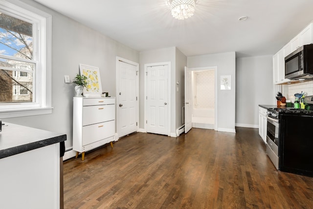 kitchen with dark wood finished floors, backsplash, white cabinetry, and appliances with stainless steel finishes