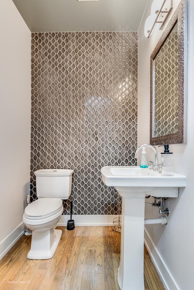 half bath with wood finished floors, toilet, and baseboards