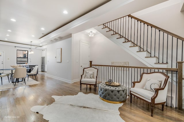 living area with stairs, recessed lighting, wood finished floors, and baseboards