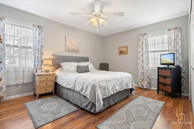 bedroom featuring visible vents, a ceiling fan, baseboards, and wood finished floors