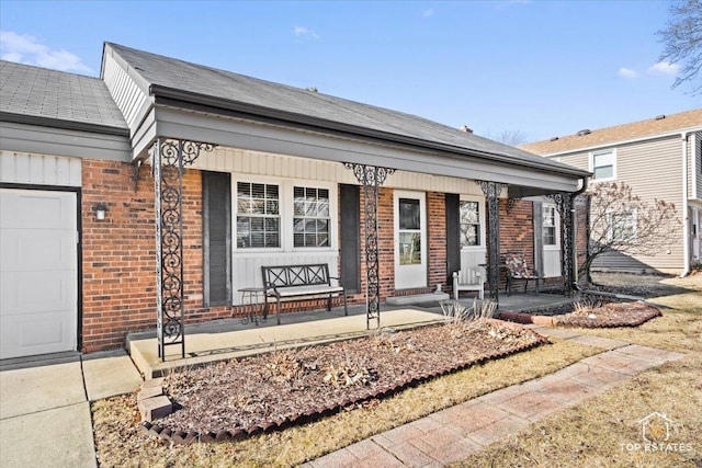 view of front of home with brick siding, a porch, and an attached garage