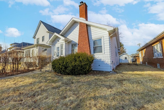 view of side of property with a chimney and a lawn