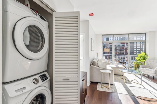 laundry room featuring laundry area, dark wood-style flooring, and stacked washer / dryer