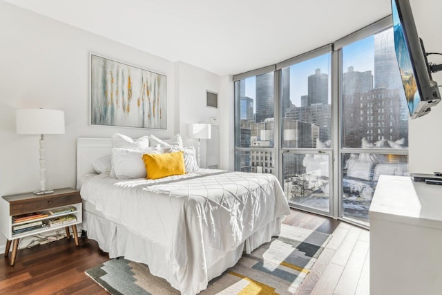 bedroom with wood finished floors, visible vents, and floor to ceiling windows