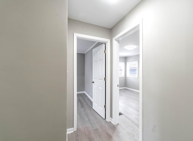 hallway featuring light wood-type flooring and baseboards