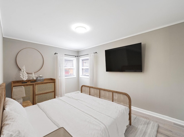 bedroom with crown molding, baseboards, and wood finished floors