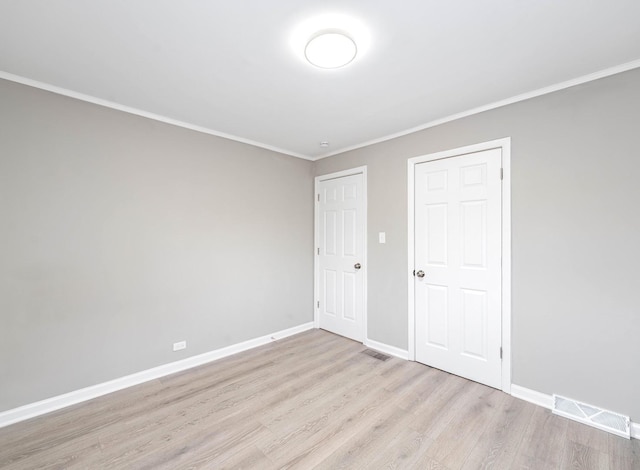 unfurnished bedroom with crown molding, wood finished floors, visible vents, and baseboards