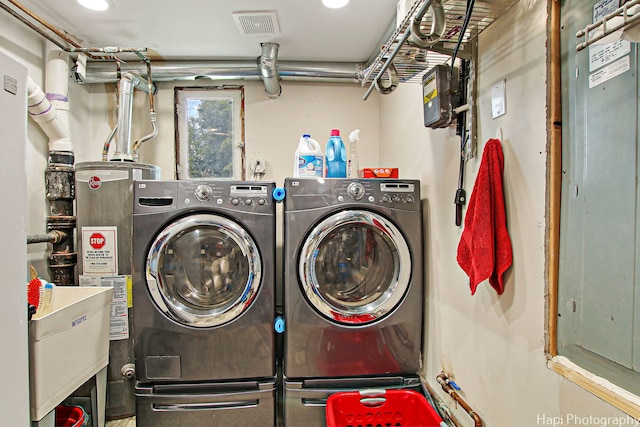 laundry room with laundry area, water heater, visible vents, and separate washer and dryer