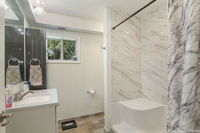 bathroom featuring visible vents, baseboards, a shower with shower curtain, stone finish floor, and vanity