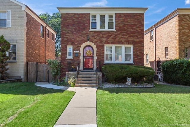 view of front of property with a front yard, brick siding, and fence