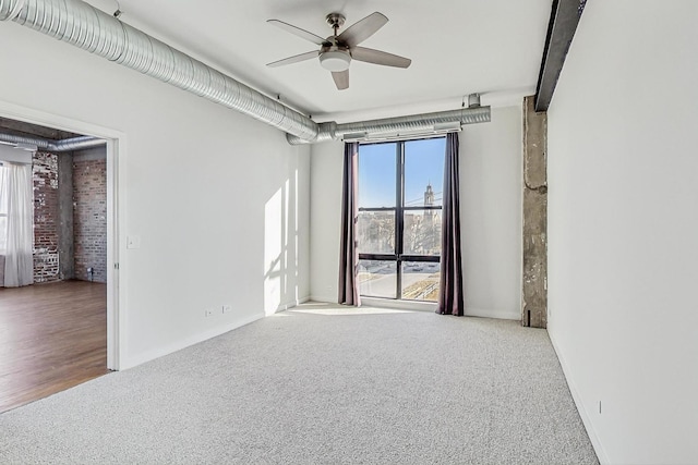 carpeted spare room featuring baseboards and a ceiling fan