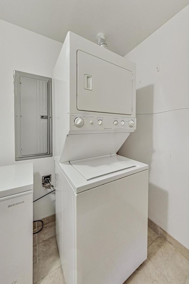 laundry room featuring laundry area, electric panel, and stacked washer / dryer