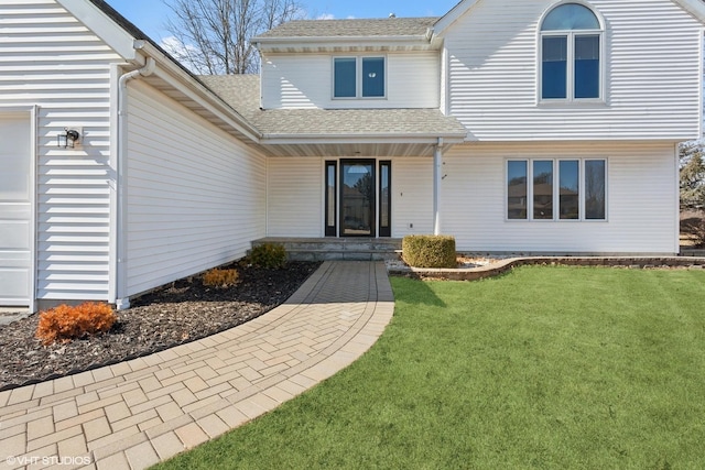 property entrance with a yard, covered porch, an attached garage, and a shingled roof