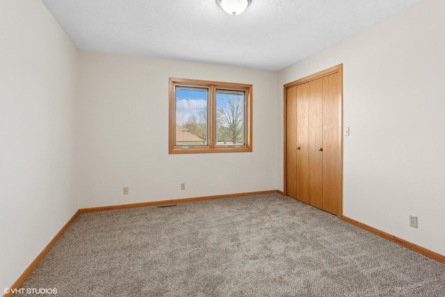 unfurnished bedroom featuring carpet flooring, visible vents, baseboards, and a closet