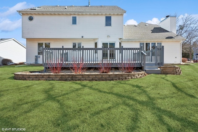 back of property with a deck, a yard, and a chimney