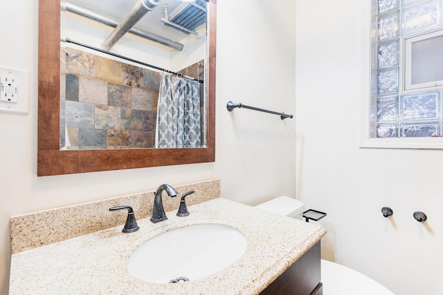 bathroom featuring toilet, curtained shower, and vanity