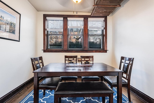 dining space with dark wood-style flooring and baseboards