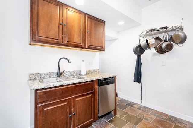 kitchen with light stone counters, a sink, baseboards, dishwasher, and stone finish flooring