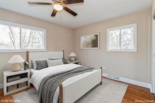 bedroom featuring wood finished floors, visible vents, baseboards, and multiple windows