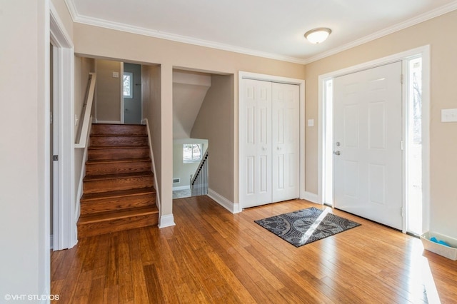 entrance foyer with stairs, ornamental molding, baseboards, and wood finished floors