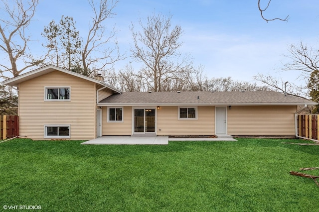 rear view of house featuring a shingled roof, a patio, a chimney, fence, and a yard