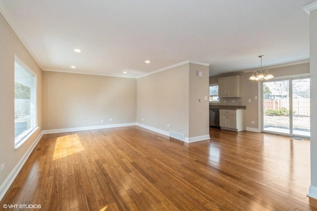 unfurnished living room with crown molding, visible vents, an inviting chandelier, light wood-style floors, and baseboards