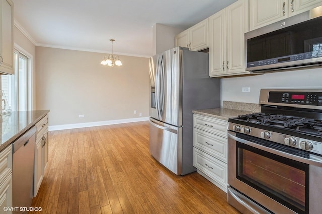 kitchen featuring appliances with stainless steel finishes, light stone counters, an inviting chandelier, crown molding, and light wood-type flooring