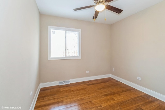 empty room featuring a ceiling fan, wood finished floors, visible vents, and baseboards