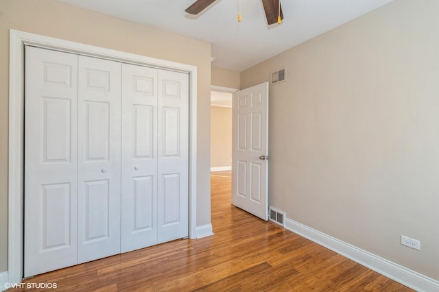 unfurnished bedroom with baseboards, visible vents, a closet, and wood finished floors