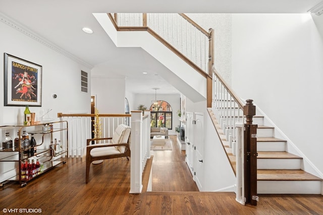 staircase with recessed lighting, a skylight, a towering ceiling, and wood finished floors