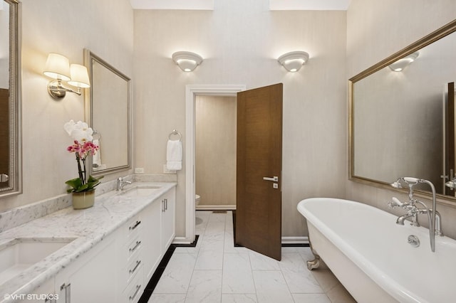 full bath with a freestanding tub, toilet, marble finish floor, and a sink