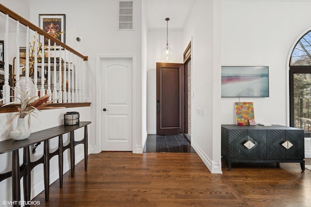 foyer with dark wood-style floors, visible vents, crown molding, and baseboards